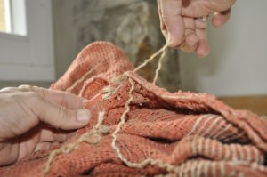 a close up picture of two hands sewing rope into a potato sack